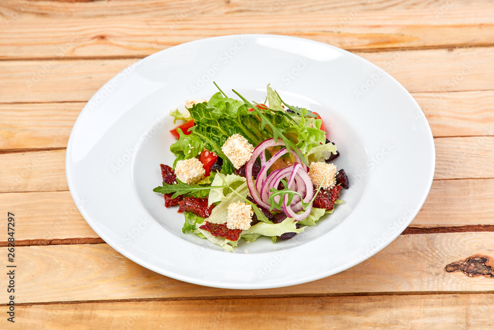 vegetarian salad with dried tomatoes and croutons on the wooden background vegetarian salad with dried tomatoes and croutons on the wooden background