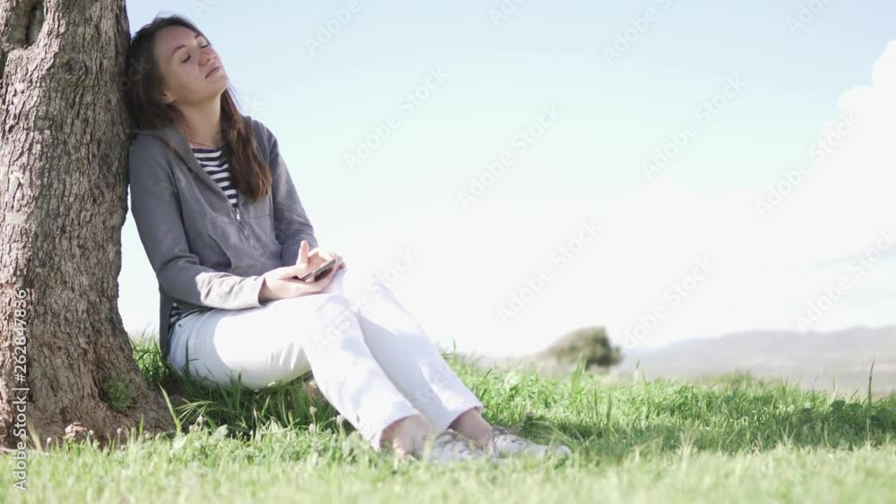 Relaxed and happy woman resting in nature. Beautiful woman chatting on a mobile phone in nature Relaxed and happy woman resting in nature. Beautiful woman chatting on a mobile phone in nature
