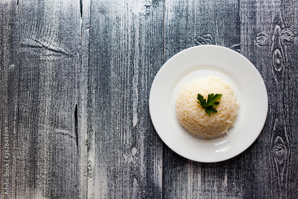 boiled rice in a white plate. wooden background. parsley boiled rice in a white plate. wooden background. parsley