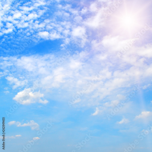 Bright sun on blue sky with white clouds. © alinamd