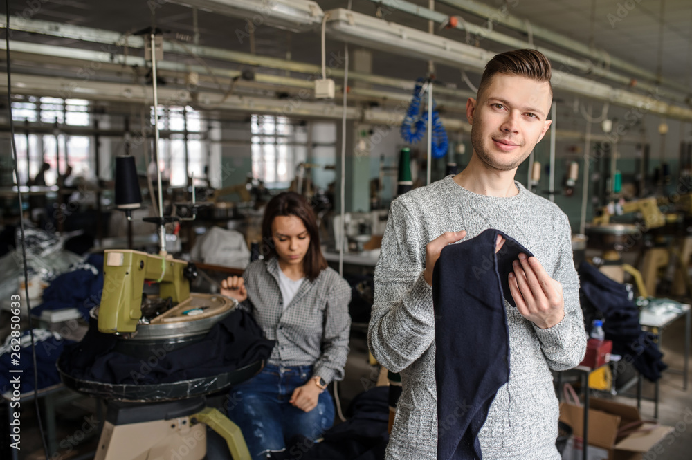 close up photo of a young man analyzing a piece of work and a woman working with linking machine for knitting in textile industry close up photo of a young man analyzing a piece of work and a woman working with linking machine for knitting in textile industry