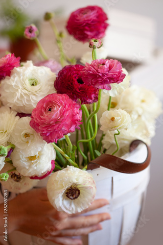 Romantic floral composition with a pink Ranunculus flowers closeup. Beautiful bouquet of flowers in white basket