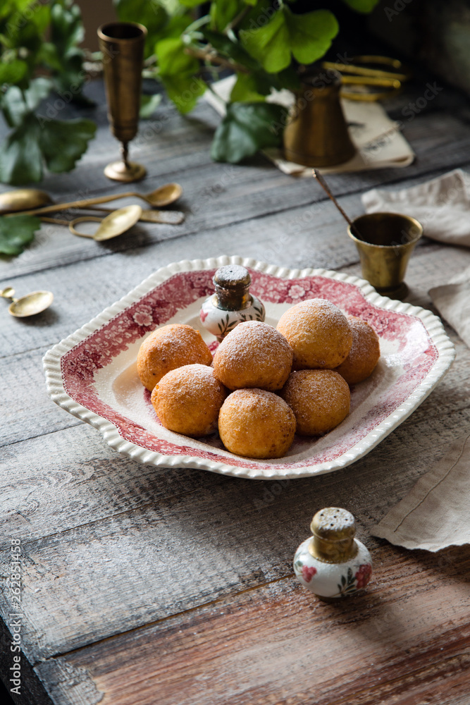 Homemade small round ball donuts sprinkled with powdered sugar on vintage plate Homemade small round ball donuts sprinkled with powdered sugar on vintage plate