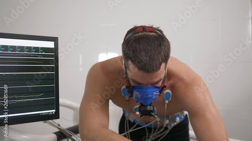 Portrait of runner wearing mask on treadmill in sports science laboratory. Tired exhausted Sports man close up running on treadmill and monitoring his fitness performance hockey player photo