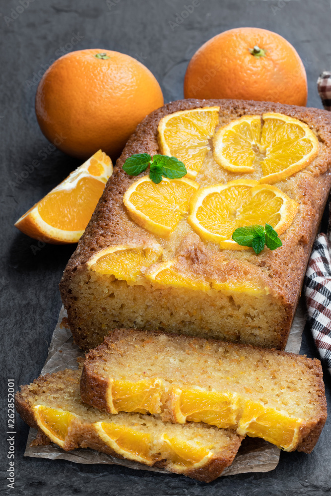 Homemade orange syrup cake on black stone background Homemade orange syrup cake on black stone background