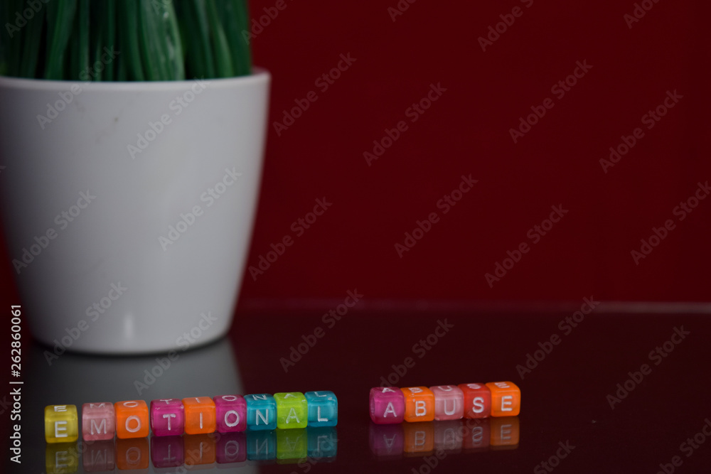 Fototapeta premium Emotional abuse text at colorful wooden block on red background. Desk office and education concept