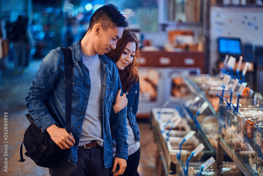 Fototapeta premium Romantic asian couple looking for something special at seafood chainese market