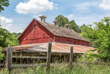 Vintage Red Barn in Ohio - An old red barn, faded from its former glory, stands among growing trees and brush in the Ohio countryside.