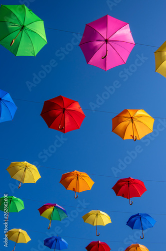 Group of umbrellas hanging on a rope isolated against blue background  wallpaper background  bright various colors scenery