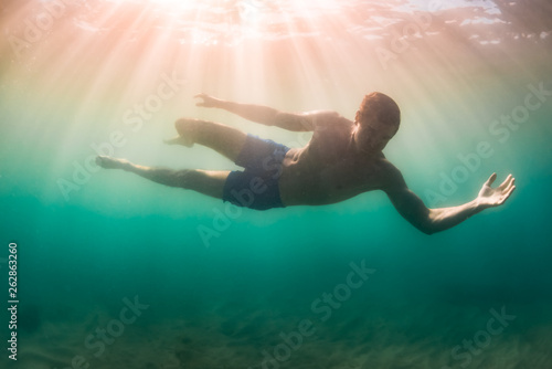 Wallpaper Mural Man suspended above sandy lake bottom in sunlight dappled murky Torontodigital.ca