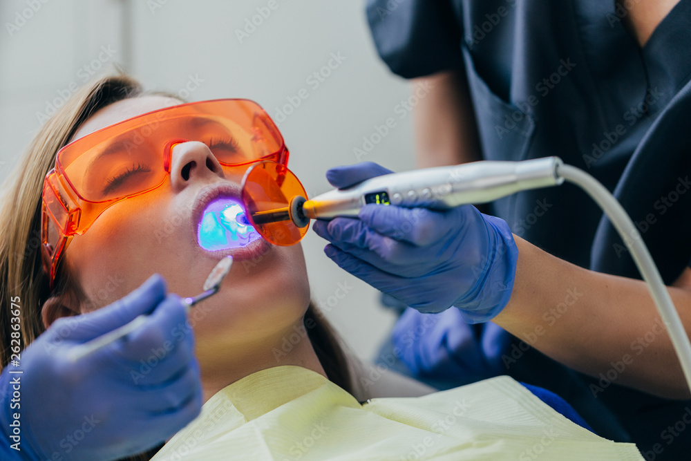 Dentist examining a patient with UV light Stock Photo Adobe Stock