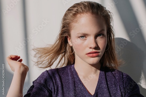 Beautiful blond girl with flying hair indoors in contrast light photo