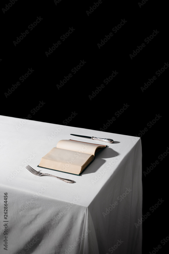 An Open book on the table, with a fork and knife An Open book on the table, with a fork and knife