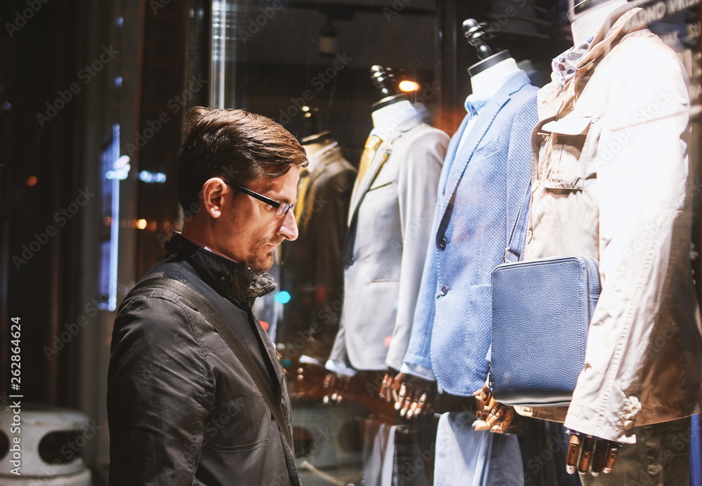 Man watching clothes through shop window glass.