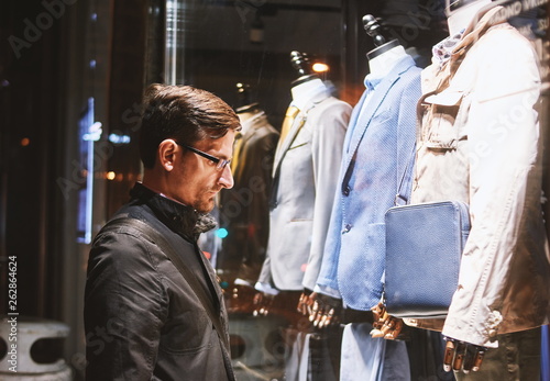 Man watching clothes through shop window glass.