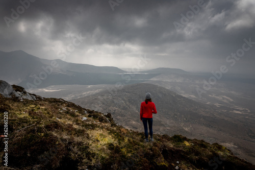 une femme en haut d'une montagne devant un paysage grandioses  sous un ciel menaçant © Olivier Tabary