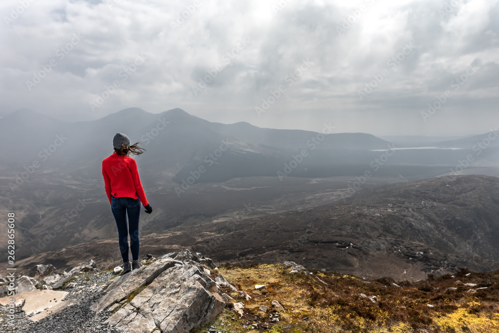une femme de dos au sommet d'une montagne admire le paysage 
