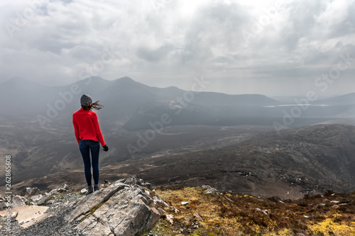 une femme de dos au sommet d'une montagne admire le paysage 