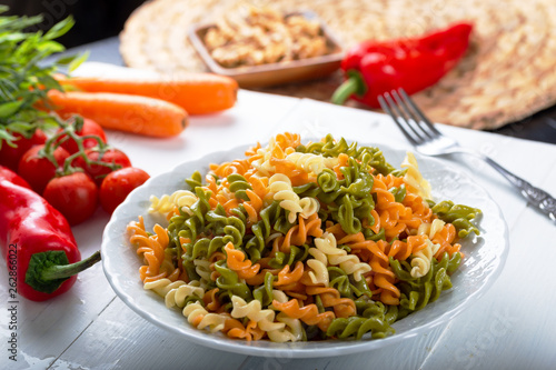 Multicolored pasta with vegetable on wooden background ve vegetables