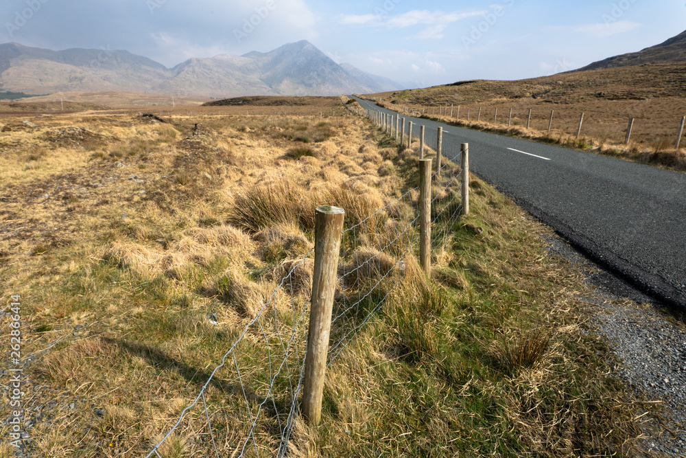 des barbelés au bord d'une route au milieu de grand espace naturels en Irlande
