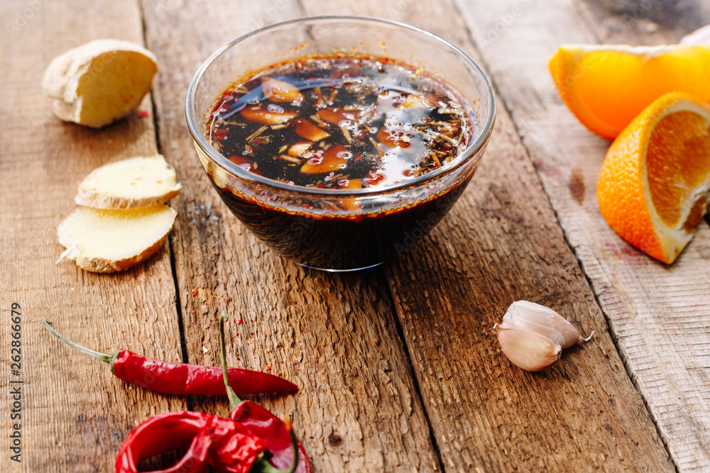 Soy sauce with chilli pepper, garlic, ginger and orange. Wooden table. Homemade. Diet.