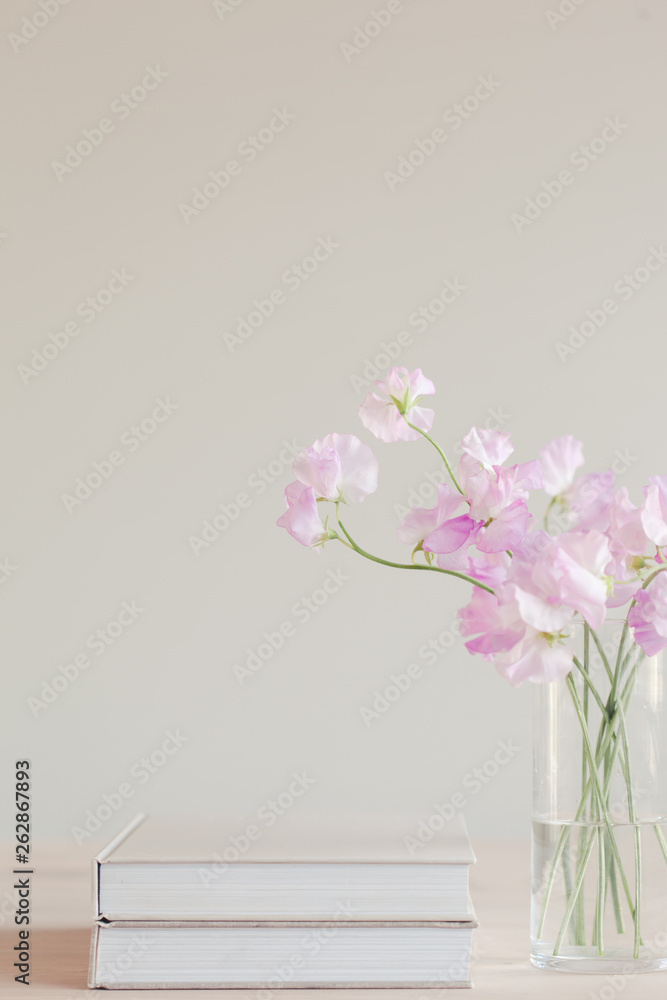 Stack of books and pretty pink sweet pea flowers in a glass vase Stack of books and pretty pink sweet pea flowers in a glass vase