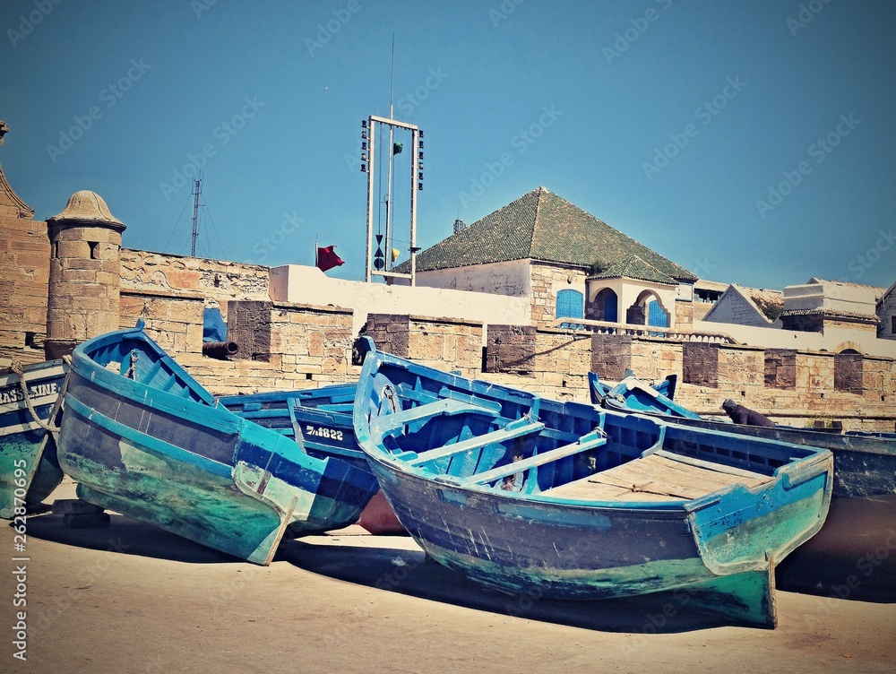 Group of blue fishing boats on the shore at the pier in the city of Essaouira Morocco