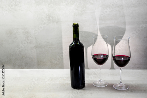 Glasses of red wine cast shadow on gray background