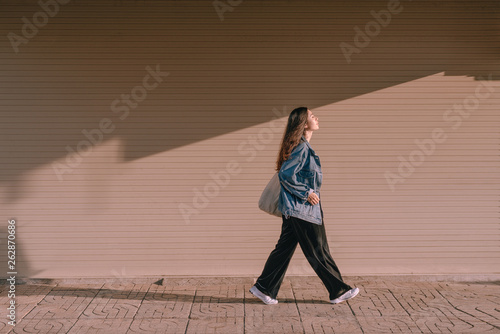 Young asian woman walking on street in the sunny day. photo
