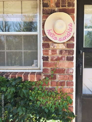 Hello Sunshine Hat Hanging on Brick Outdoor Ivy Covered Wall photo