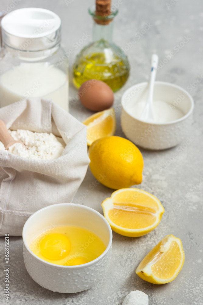 Ingredients for making cake - flour, eggs, milk or buttermilk, olive oil, sugar, lemon, baking powder. Food background. Bake sweet cake dessert concept. Copy space. Ingredients for making cake - flour, eggs, milk or buttermilk, olive oil, sugar, lemon, baking powder. Food background. Bake sweet cake dessert concept. Copy space.
