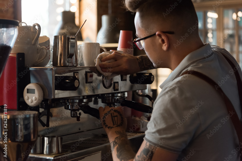 Tattooed barista working with machine Tattooed barista working with machine