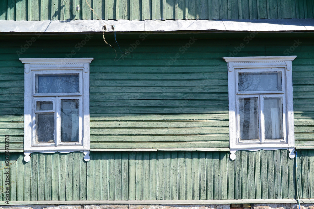 Fototapeta premium Vintage windows jamb of traditional old wooden russian house in village, shabby background of teal color, close up with copy space