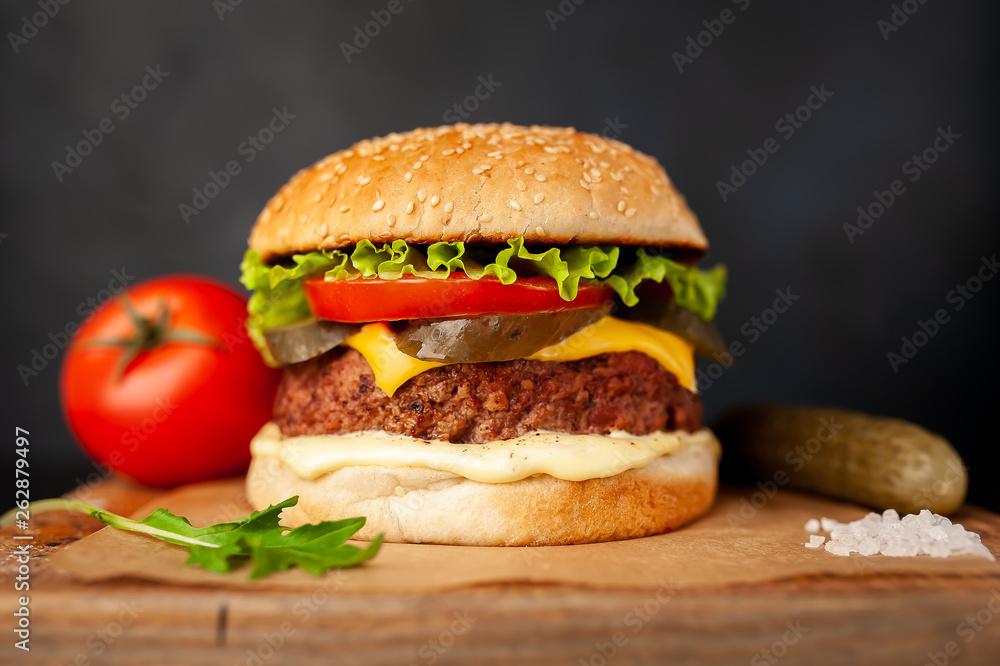 Homemade hamburger with lettuce, tomato, cheese and cucumber on a cutting board Homemade hamburger with lettuce, tomato, cheese and cucumber on a cutting board