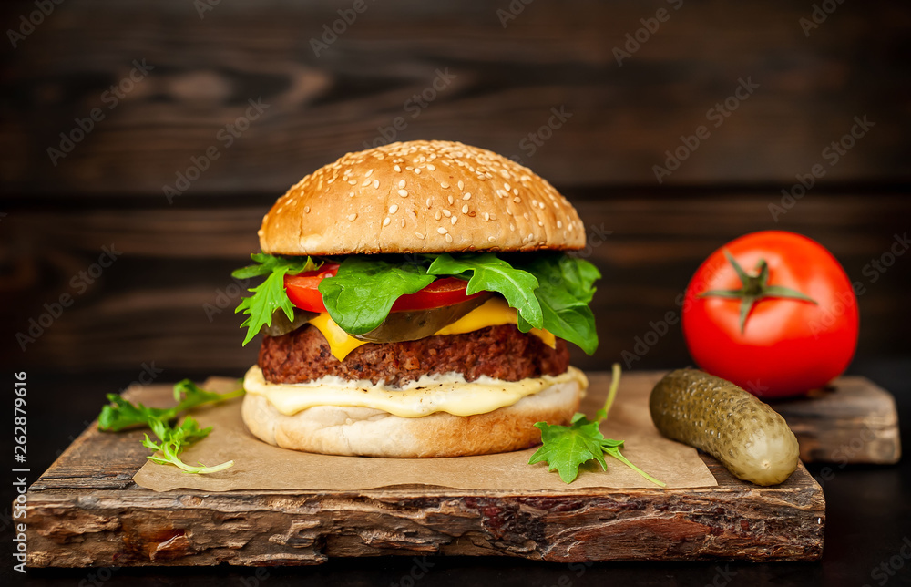 Homemade hamburger with lettuce, tomato, cheese and cucumber on a cutting board Homemade hamburger with lettuce, tomato, cheese and cucumber on a cutting board