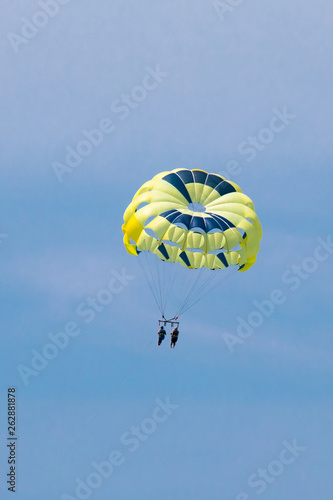 Two people parasailing above the Gulf of Mexico near Englewood, Florida, USA, in early spring, with soft clouds and blue sky as backdrop