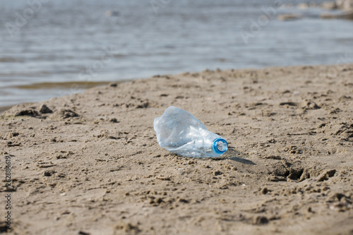 smashed pet disposable plastic bottle on beach sand. Plastic pollution