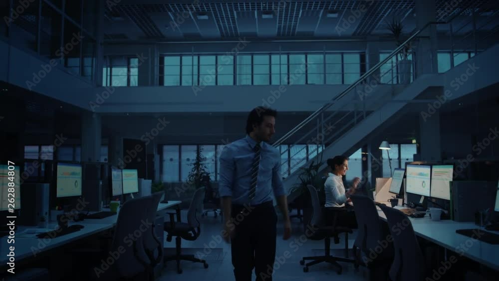 Working Late at Night in the Office: Businesswoman Using Desktop Computer, Analyzing, Using Documents, Solving Problems, Finishing Project. Colleague Says Goodbye and Leaves Working Late at Night in the Office: Businesswoman Using Desktop Computer, Analyzing, Using Documents, Solving Problems, Finishing Project. Colleague Says Goodbye and Leaves