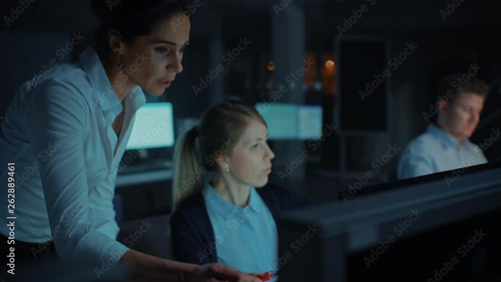 Beautiful Businesswoman Uses Desktop Computer, Consults Her Project Manager about Documents with Graphs and Statistics, Finishing Important Project. Working Late at Night in Big Corporate Firm Office Beautiful Businesswoman Uses Desktop Computer, Consults Her Project Manager about Documents with Graphs and Statistics, Finishing Important Project. Working Late at Night in Big Corporate Firm Office