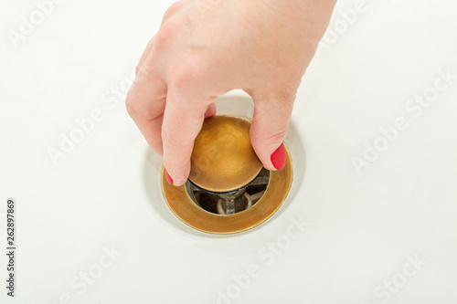 Female hand holds bathtub drain plug