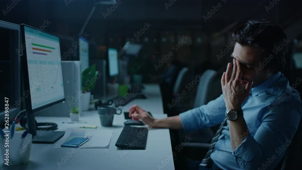 In the Office at Night Overworked Tired Office Worker Uses Desktop Computer Yawning, Drinks Coffee. Tired Exhausted Businessman Finishing Important Project In the Office at Night Overworked Tired Office Worker Uses Desktop Computer Yawning, Drinks Coffee. Tired Exhausted Businessman Finishing Important Project