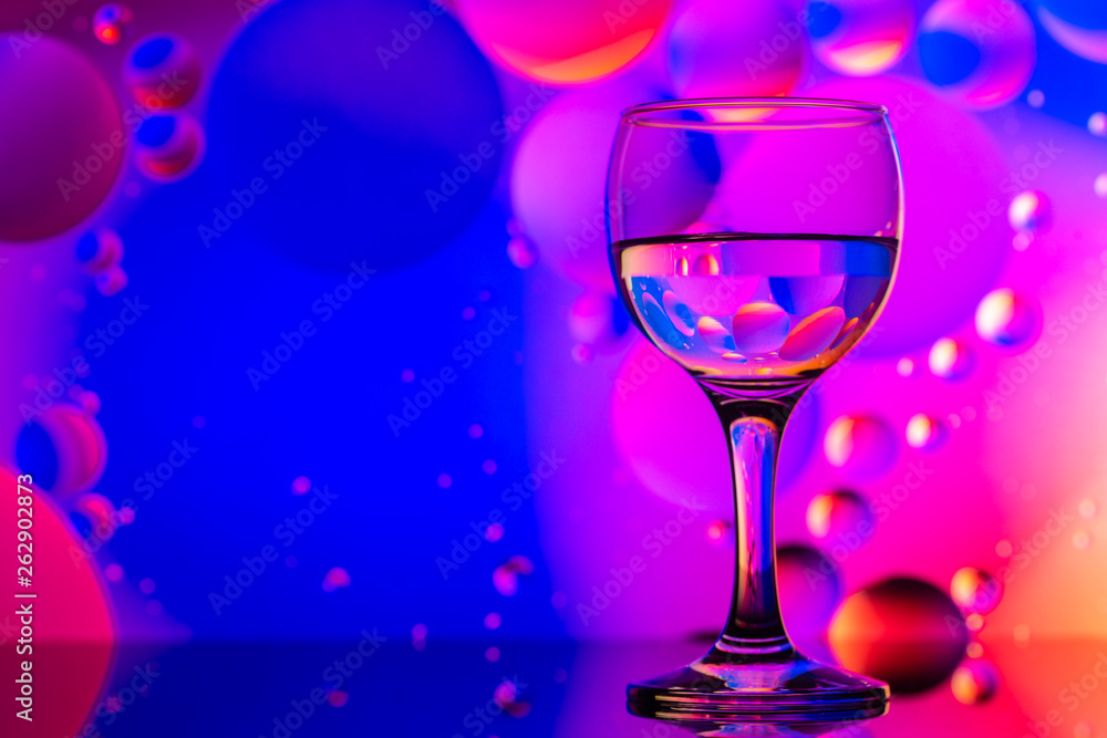transparent glasses with water and oily drops on colorful background transparent glasses with water and oily drops on colorful background