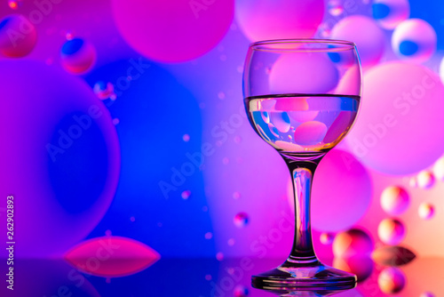 transparent glasses with water and oily drops on colorful background 