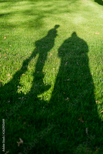 Shadows of two people in the grass on a very sunny day