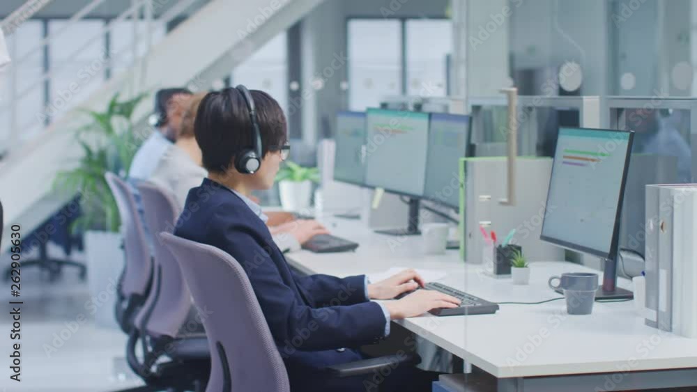 Team of Handsome and Beautiful Diverse Multicultural Customer Service Operators Working at a Busy Modern Call Center with Specialists Wearing Headsets and Actively Taking Calls. Team of Handsome and Beautiful Diverse Multicultural Customer Service Operators Working at a Busy Modern Call Center with Specialists Wearing Headsets and Actively Taking Calls.
