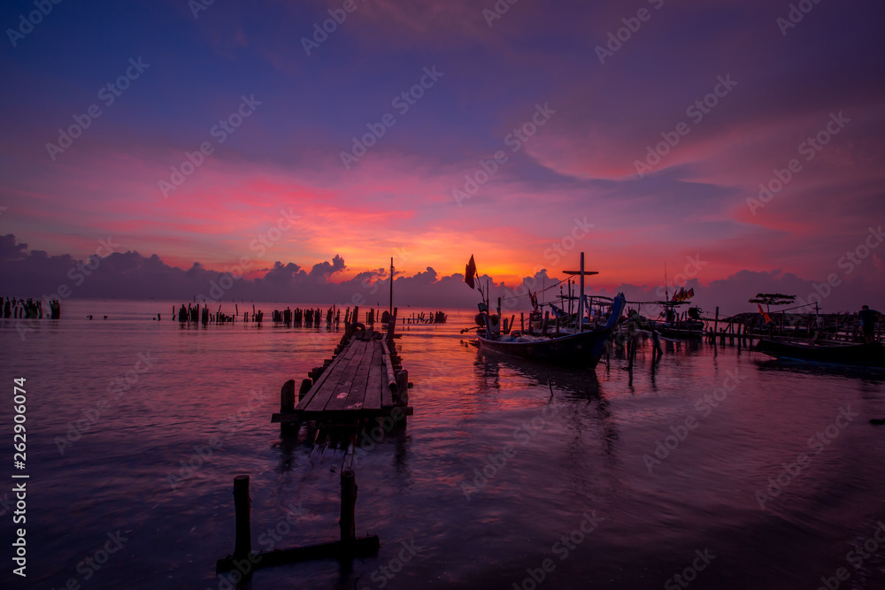 The background of the morning sunrise scenery by the sea, the fishing boats parked in the blurred beauty of the sea breeze that passes through, is the beauty of nature during traveling.