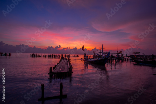 The background of the morning sunrise scenery by the sea, the fishing boats parked in the blurred beauty of the sea breeze that passes through, is the beauty of nature during traveling. © bangprik