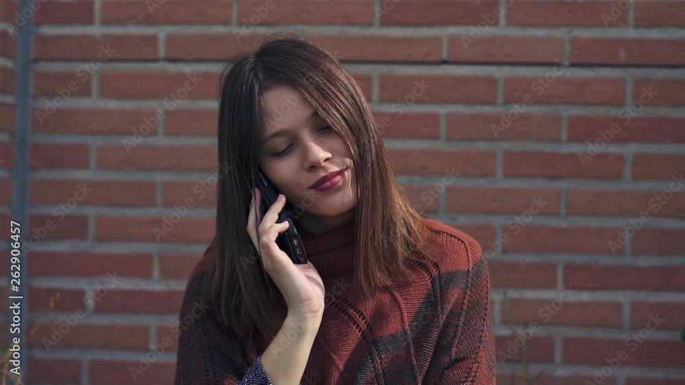 Beautiful young Woman talking to the phone,outdoors, brick wall background, Slow motion clip with gimbal Beautiful young Woman talking to the phone,outdoors, brick wall background, Slow motion clip with gimbal