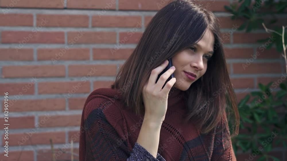 Beautiful young Woman talking to the phone,outdoors, brick wall background, Slow motion clip with gimbal Beautiful young Woman talking to the phone,outdoors, brick wall background, Slow motion clip with gimbal