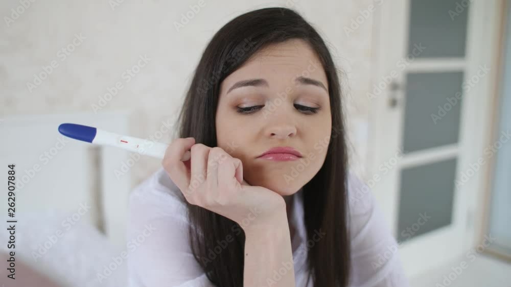 Depressed woman with pregnancy test at the room Depressed woman with pregnancy test at the room